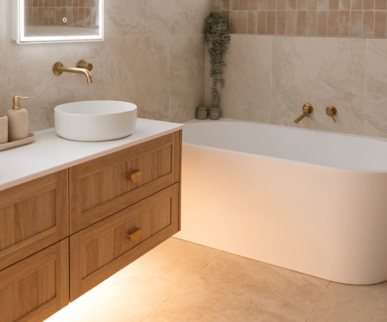 Timber vanity with brass tapware beside a freestanding bath in a renovated Central Coast bathroom