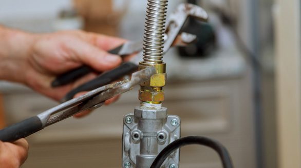 Licensed gas fitter tightening a flexible gas connection with a spanner