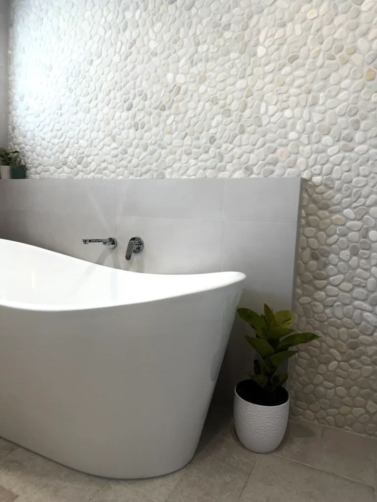 Freestanding bath and pebble feature wall in a completed Central Coast bathroom renovation by ZC Plumbing