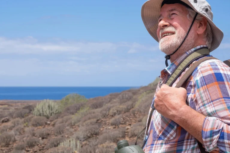 Smiling older man in a hat walking outdoors near the coast