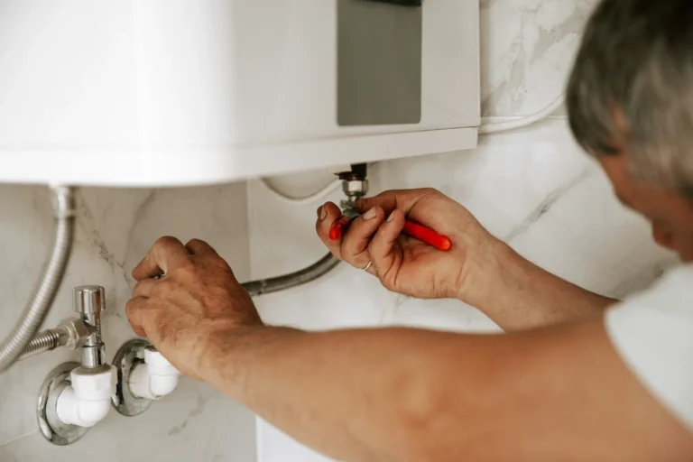 Plumber tightening the pipe connections under a sink