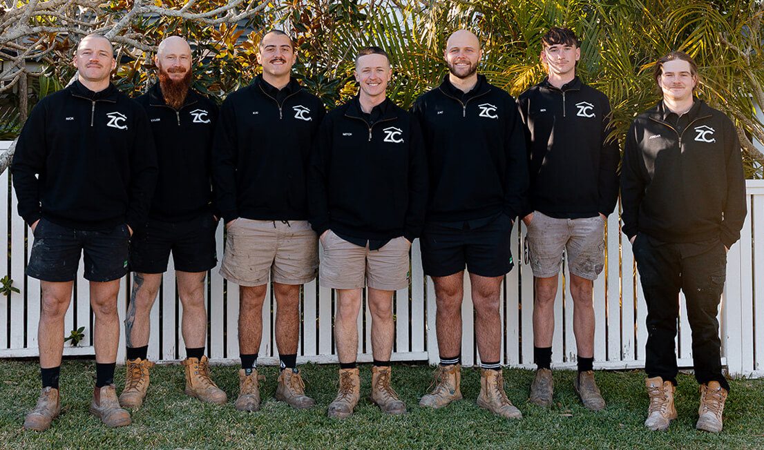 The ZC Plumbing team standing outside in a backyard garden