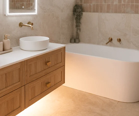 Timber vanity with brass tapware beside a freestanding bath in a renovated Central Coast bathroom