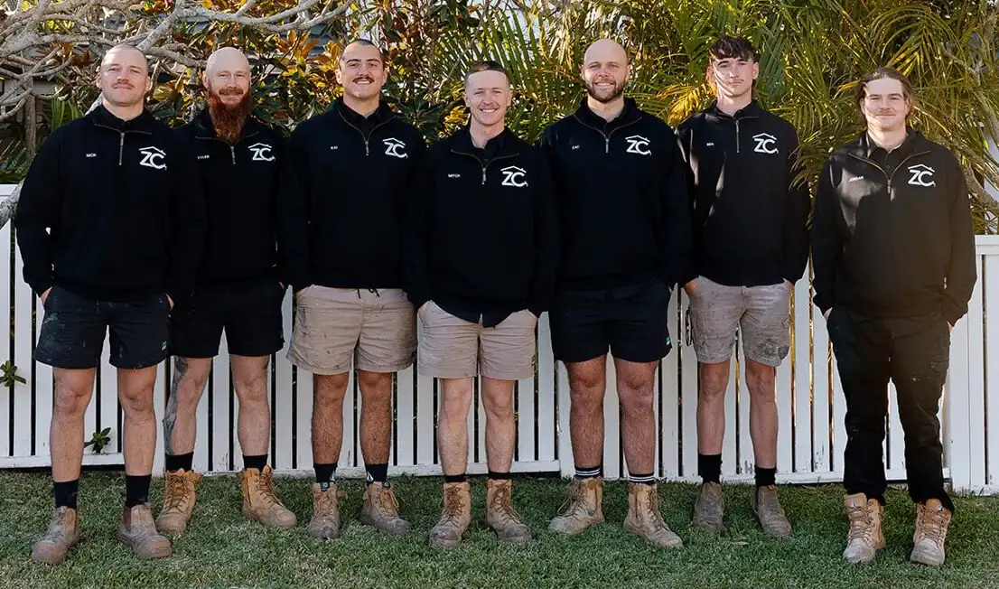 The ZC Plumbing team standing outside in a backyard garden